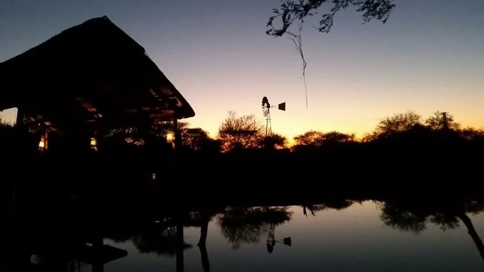 Thatched roof and pool silhouetted at sunset, Chinaka chalets and Luna eco Lodge