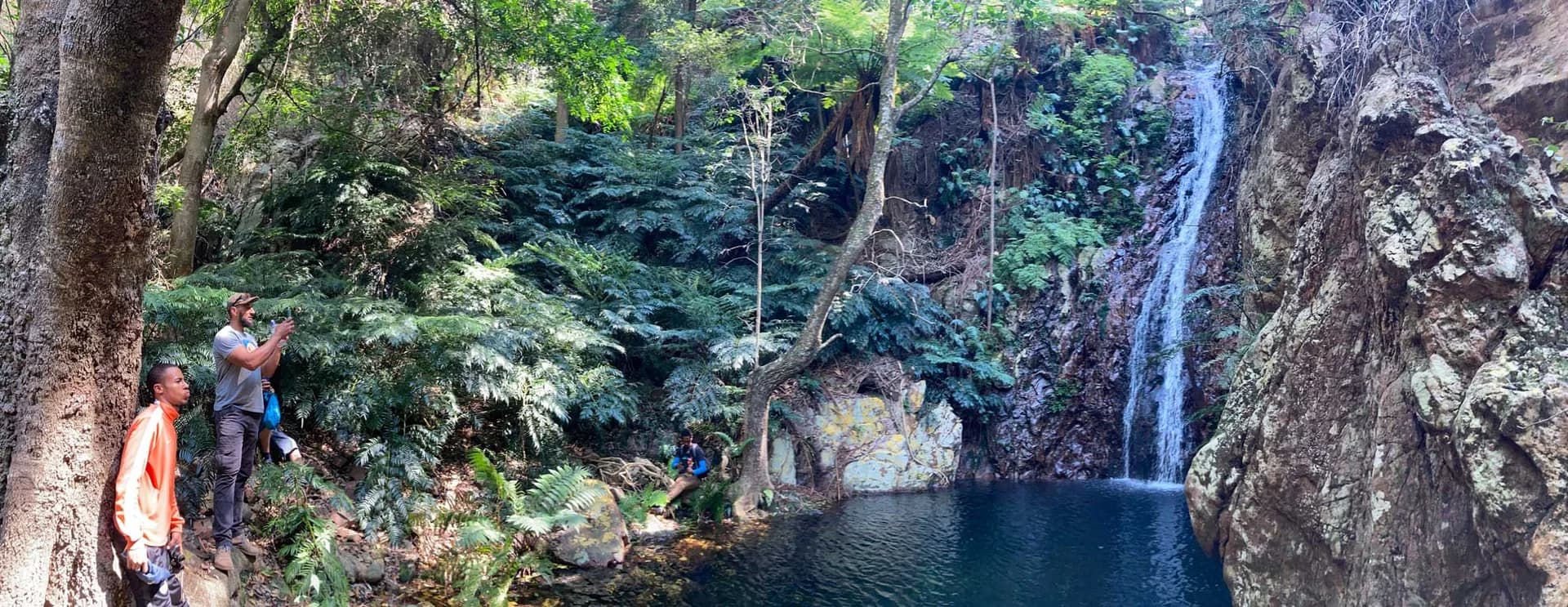 Two walkers beside a forest waterfall and rock pool, Buysdorp Moutoon Trail